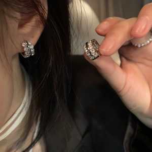 Detailed view of silver leaf hollow hoop earrings with zircons worn on earlobe