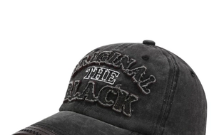 Close-up of Original The Black 3D embroidery on washed vintage charcoal baseball cap