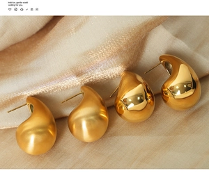 Detail view of gold teardrop earrings in polished and matte finish on silk fabric