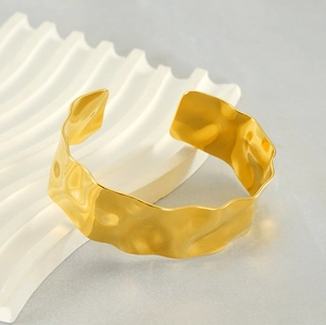 Macro detail of 18K gold-plated cuff featuring hammered texture and wavy edges