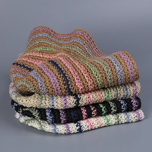 Detail of colorful striped hand-crocheted straw bucket hats in stacked arrangement