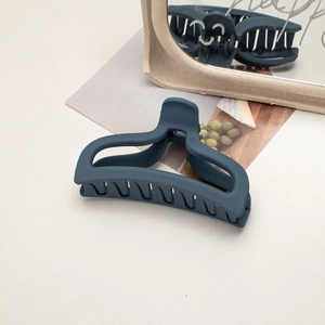 Detailed close-up of a large matte navy blue hair claw clip against a lifestyle backdrop