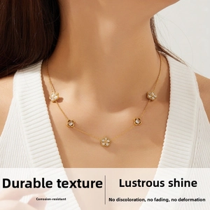 Close-up of elegant gold chain necklace with five diamond-studded floral pendants on neck