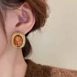 Detail of vintage gold-trimmed resin earring with amber texture on a model