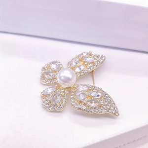 Vue détaillée de la broche papillon dorée avec perle blanche et cristaux scintillants