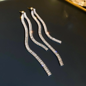 Macro shot of silver tassel earrings with sparkling white cubic zirconia in wave shape