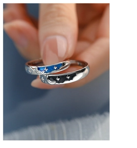 Macro shot of silver sun and moon couple rings with blue and black enamel star details