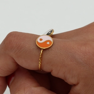 Macro detail of 18K gold plated ring with white and orange enamel Tai Chi design