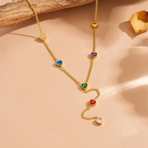 Detailed shot of gold heart necklace with colorful crystals on a rustic branch