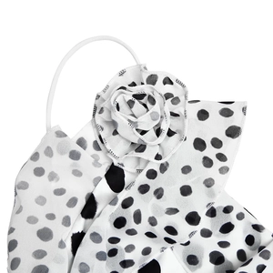 Dettaglio dell'abito in chiffon a pois con fiore 3D sulla spallina sottile bianca