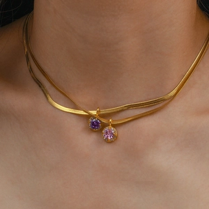 Close-up of a double-layered gold snake chain necklace with purple and pink zircon pendants
