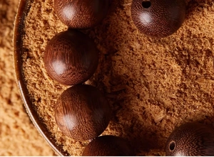 Macro shot of natural dark brown sandalwood beads with fine wood grain and texture