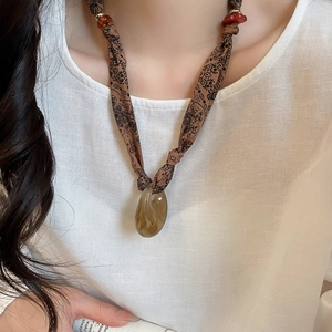 Close-up of a vintage brown printed fabric necklace with an amber acrylic pendant