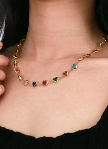 Detail of colorful heart-shaped zircon necklace with gold chain on model neck