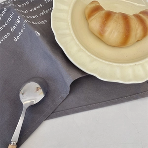 Close-up of a minimalist dark gray linen placemat with white printed text in a cafe setting