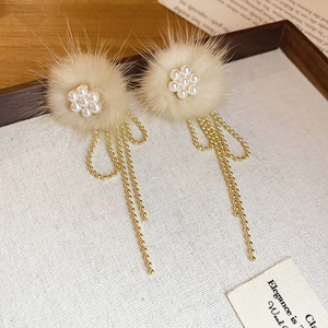 Macro detail of plush floral earrings with pearl petals and golden chain tassels