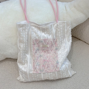 Close-up of white velvet tote bag featuring floral lace applique and pink shoulder straps