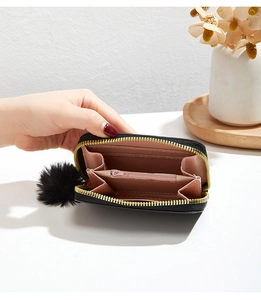 Detailed interior of a black plush coin purse with pink card slots and a pompom charm
