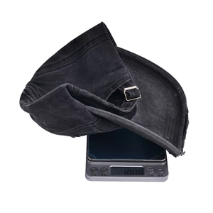 Distressed black cotton baseball cap on a digital scale showing weight of 100.6g