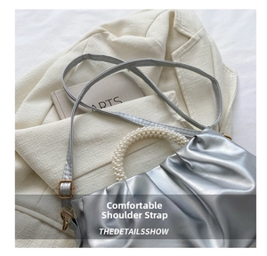 Detail of silver pleated cloud bag featuring pearl beaded handle and slim shoulder strap