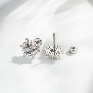 Silver snowflake earrings with grey gems and screw back closure shown on white fabric