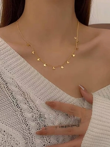 Close-up of a gold butterfly necklace on a model wearing an off-shoulder sweater