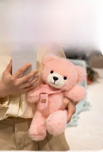Close-up of soft pink teddy bear featuring a knit scarf with a smile label detail