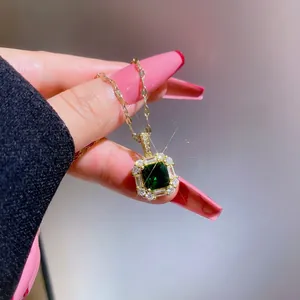 Macro shot of an emerald-style square gold pendant necklace with shimmering zircons