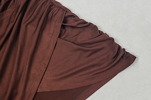 Detail view of the double-layered hem and soft pleated texture on the brown dress