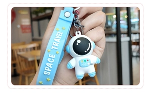 Détail du porte-clés astronaute avec sangle en silicone bleue et texte Space Travel