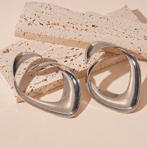 Macro detail of irregular silver earrings with metallic luster on stone display