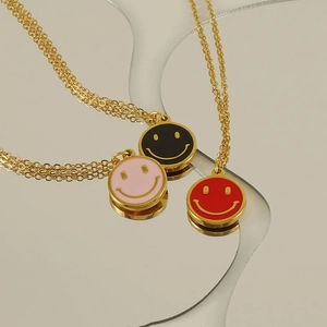 Three 18K gold-plated stainless steel necklaces with pink, red, and black smiley face pendants