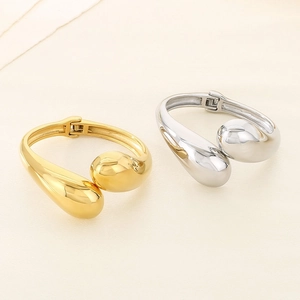 Detailed view of irregular crossover open bangles in polished gold and silver finishes