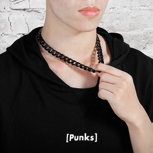 Close-up of a black stainless steel Cuban chain necklace worn by a model in punk style