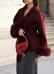 Detail of wool coat featuring burgundy fur cuffs and a leather saddle bag in a street style