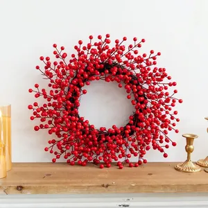 Classic red berry Christmas wreath with bow on wooden mantel with golden candles