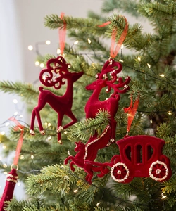 Détail d'ornements de rennes et carrosses floqués rouges avec paillettes dorées sur un sapin