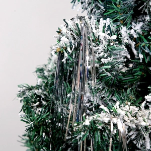 Close-up of shiny silver tinsel garlands on snow-dusted green Christmas tree branches