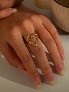Detail of a golden heart ring featuring a unique hammered texture and adjustable open band