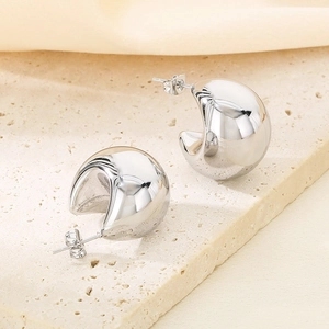 Détail macro de boucles d'oreilles créoles argentées sur un socle en pierre