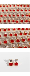 Close-up of heart and rectangular red earrings with clear stones and gold trim