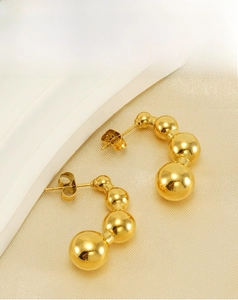 Detail of 18k gold plated stainless steel pea earrings with triple bead gradient design
