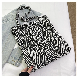 Detailed close-up of a black and white zebra print canvas tote bag on a casual denim jacket