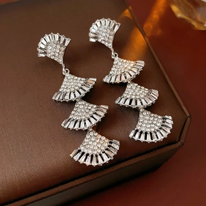 Macro shot of silver tiered fan-shaped earrings with crystals on a jewelry box lid