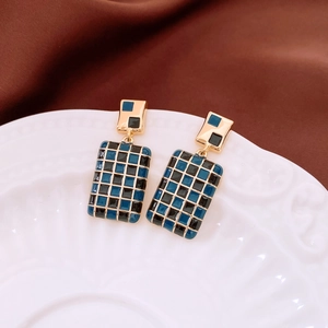 Detail of gold-plated rectangle earrings with blue and black checkered enamel design