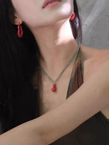 Close-up of red gourd pendant necklace and earrings set worn by a model