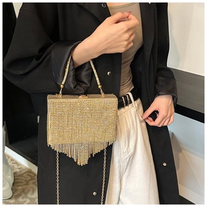 Macro detail of gold evening clutch featuring sparkling rhinestones and V-shaped tassels