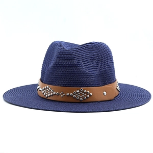 Detailed texture of navy woven straw hat with brown leather band and silver metal studs