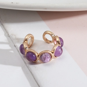 Vue détaillée d'une bague ajustable dorée ornée de cinq pierres violettes serties clos