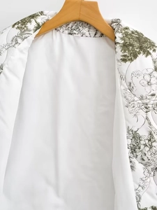 Détail du col à revers vintage avec imprimé floral vert sur un manteau en coton blanc ample